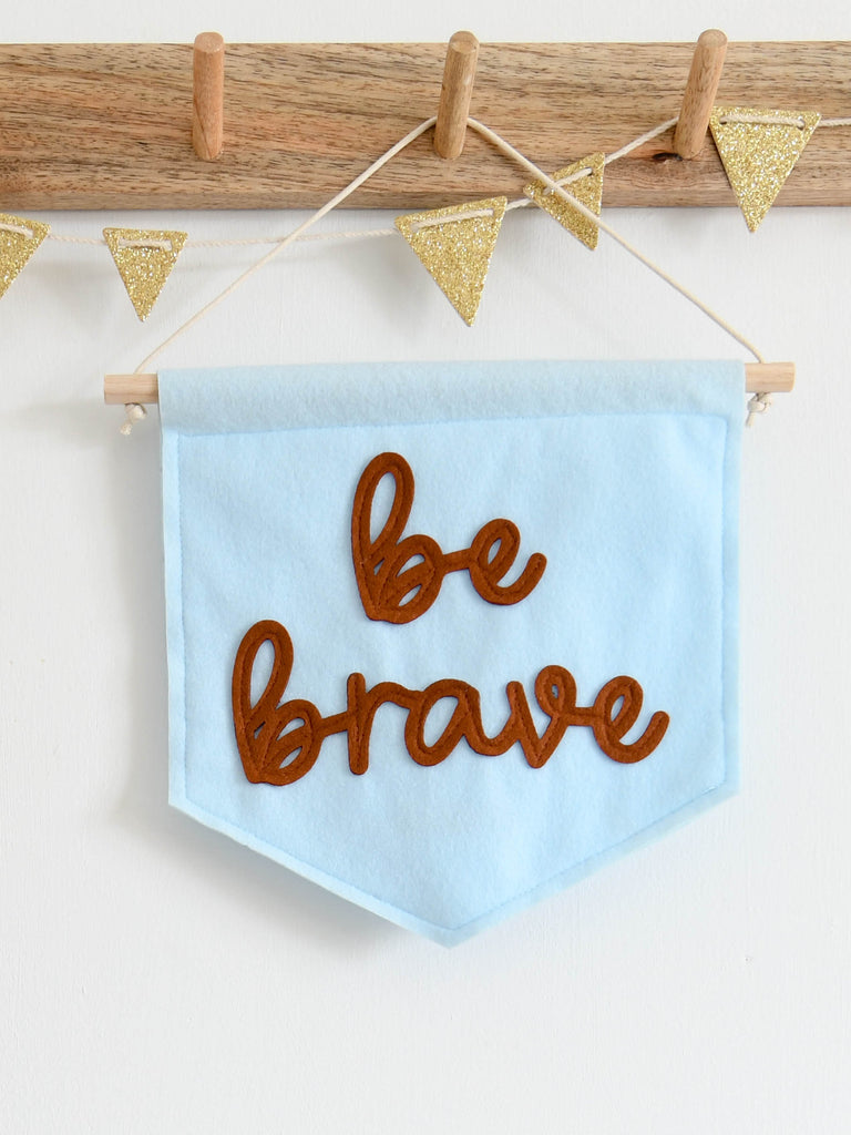 mini felt banner with be brave sewn on in cursive text.