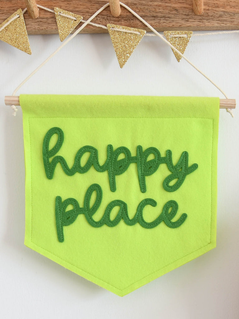 mini felt banner with the words happy place sewn on hung from a hook.