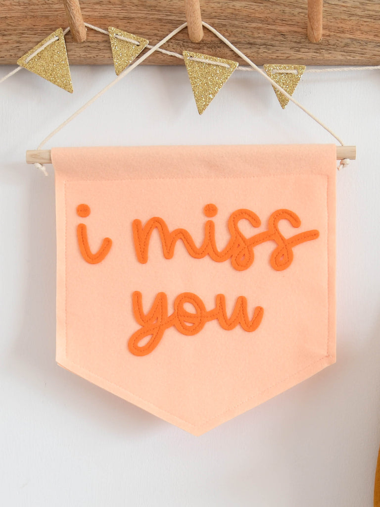 peach banner with i miss you sewn on in orange cursive font.