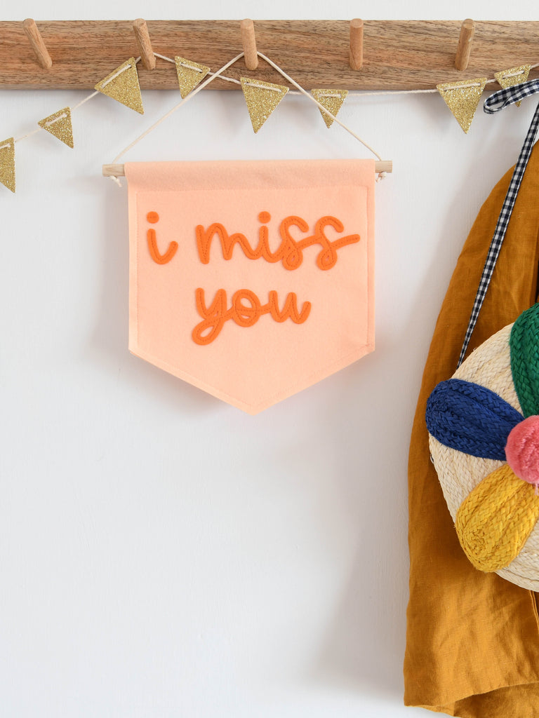 mini felt banner with the words i miss you sewn on in cursive text.