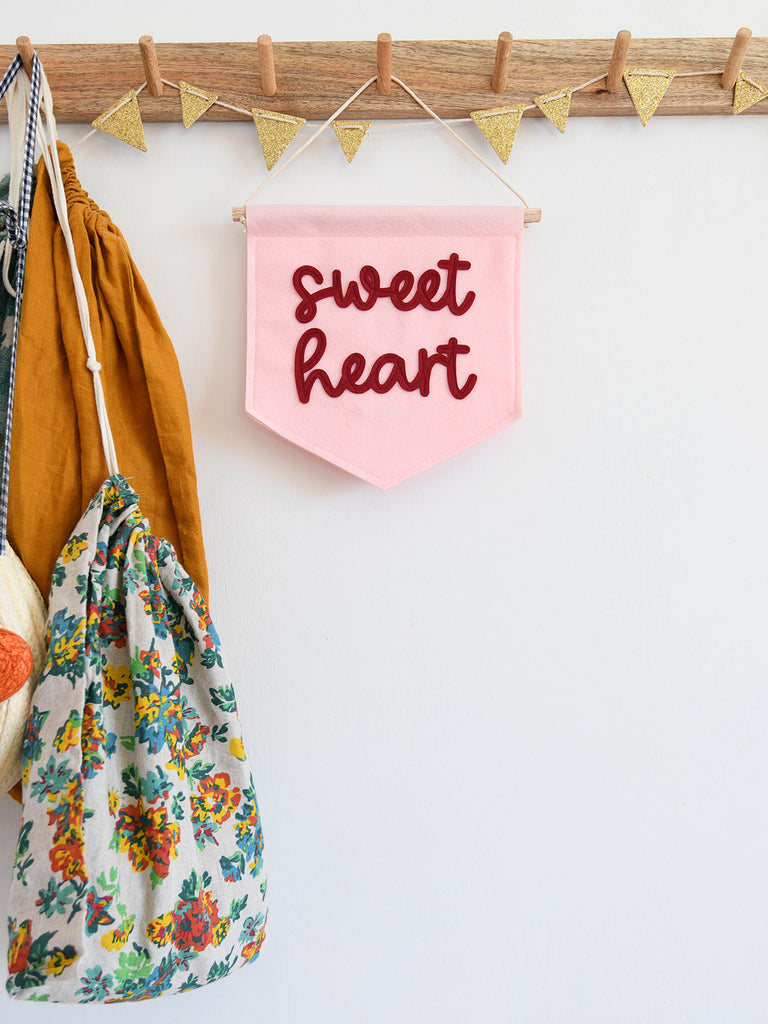 pale pink mini felt banner with the word sweet heart sewn on in dark red.
