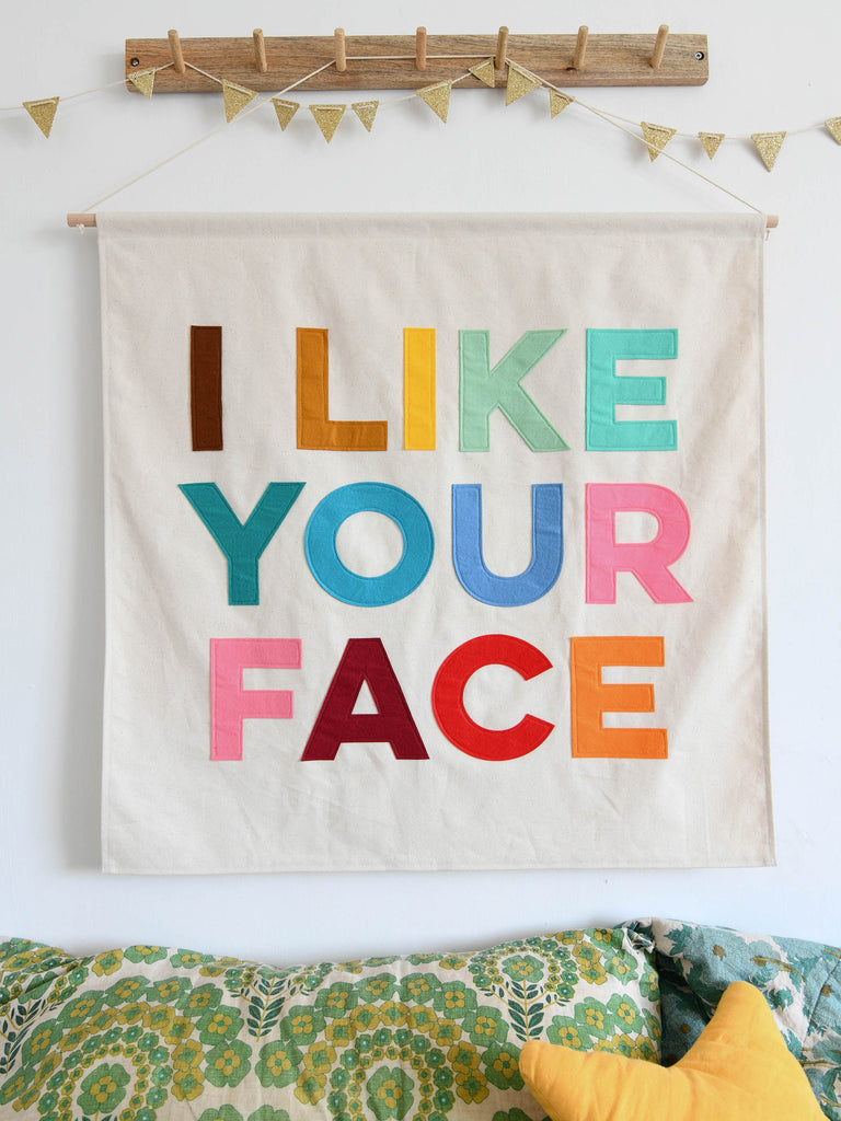 Large canvas banner with the words I like your face sewn on in felt letters.
