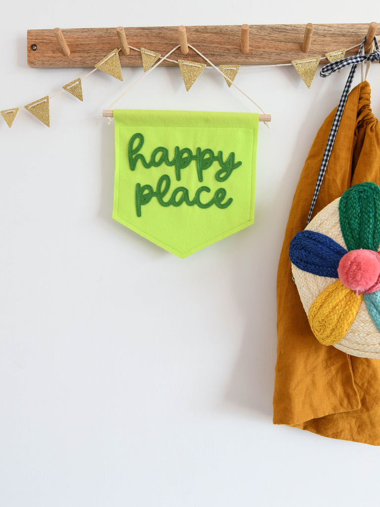 happy place mini felt wall banner hung from hook.