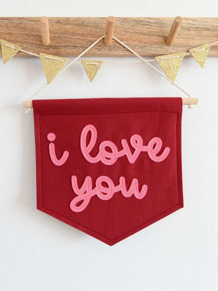 mini felt banner with the words i love you sewn on in cursive pink font.