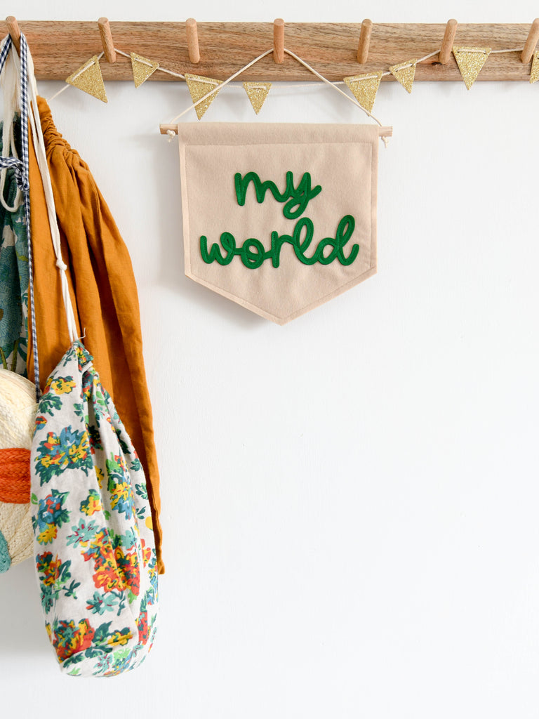 mini felt banner with my world sewn on in cursive text.