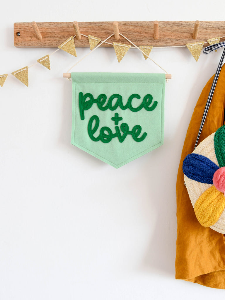 felt banner with the words peace and love sewn on in cursive font.